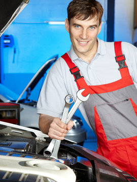 Smiling motor mechanic is working in a garage