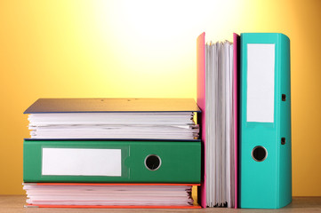 bright office folders on wooden table on yellow background.