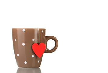 Brown cup and tea bag with red heart-shaped label isolated