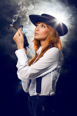 Beautiful girl in a hat, with a revolver