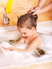 Kid washing hair by shampoo .