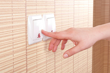 Hand pressed to switch on the wall