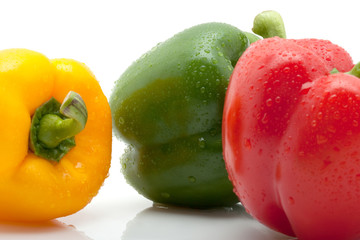 Nahaufnahme grüne, gelbe und rote Paprika mit Tropfen vor weiss