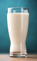 glass of milk on wooden table on blue background