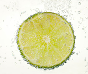 slice of lime in the water with bubbles