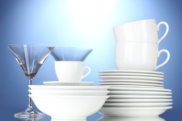 empty bowls, plates, cups and glasses on blue background