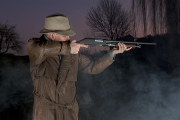 Fototapeta premium man with cowboy hat, long leather coat and riot gun