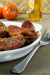 Dried tomatoes in white bowl on a wooden table