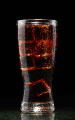 Glass of cola with ice on black background