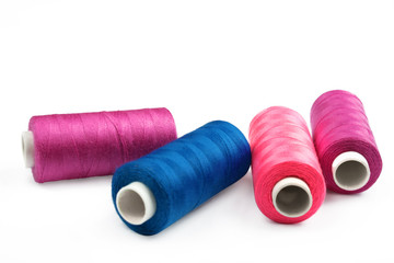 Pile of coloured bobbins of lurex thread isolated on white