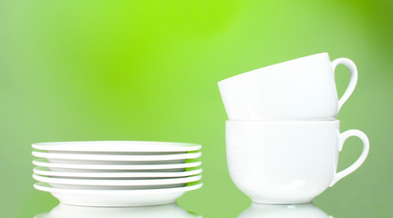 Clean plates and cups on green background