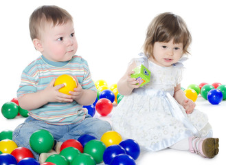 Fototapeta na wymiar The little girl and boy plays multi-coloured balls isolated