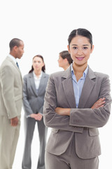 Businesswoman smiling and crossing her arms with co-workers
