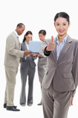 Businesswoman smiling and approving with co-workers in the backg