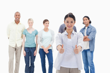 People behind a woman smiling with her thumbs-up