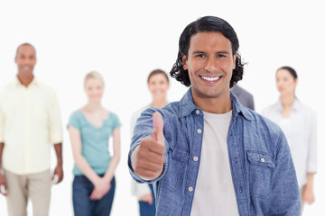 Close-up of a man with his thumb-up with people behind