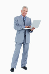 Naklejka na ściany i meble Smiling mature tradesman with his laptop