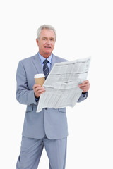 Mature tradesman holding news paper and paper cup