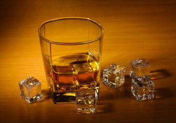 glass of scotch whiskey and ice on wooden table