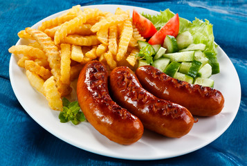 Grilled sausages, French fries and vegetables