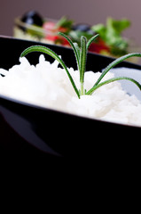 Rice in black bowl on salad background