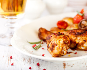 Roasted chicken legs and a glass of beer in background