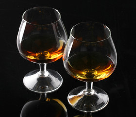 Two glasses of cognac on black background