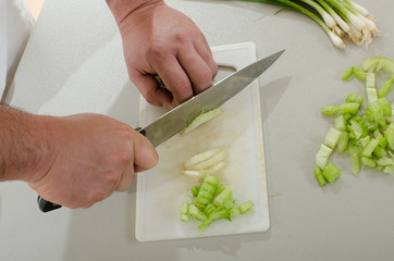 latin american man chopping onion leaves and celery