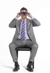 Joven ejecutivo sentado observando con binoculares.