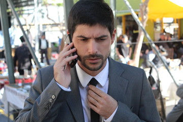 A young businessman is talking on his smartphone at the market