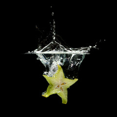 carambola splashing in water over black background