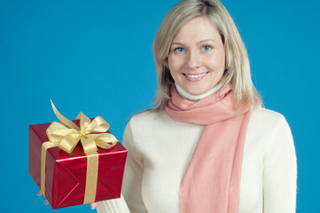 Happy caucasian young woman with a gift box over blue background