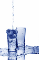 A glass is overfilled with water and an empty glass