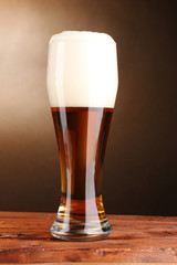 beer in glass on wooden table on brown background