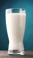 glass of milk on wooden table on blue background