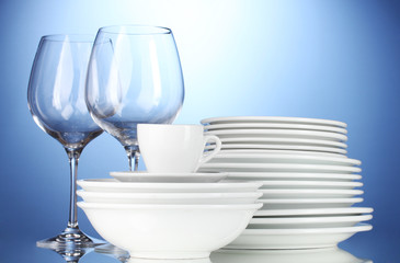empty bowls, plates, cups and glasses on blue background