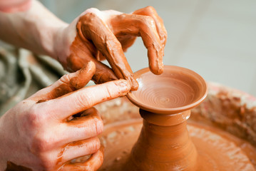 hands of a potter, creating an earthen jar on the circle