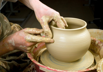 hands of a potter, creating an earthen jar of white clay