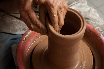 hands of a potter, creating an earthen jar on the circle