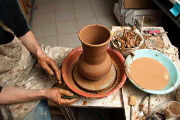 hands of a potter, creating an earthen jar on the circle