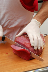 Cortando carne roja sobre una tabla de madera.