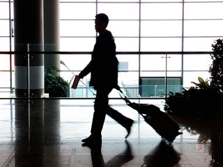 businessman walking in airport with suitcase