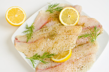 Raw tilapia fillets marinated in lemon juice and herbs