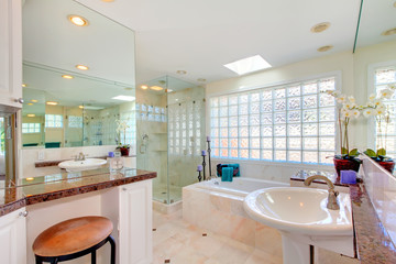 Large bright bathroom with double sinks and large tub.