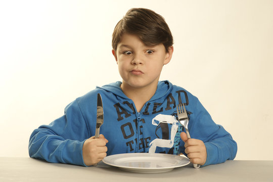 Kleiner Junge sitzt vor einem leeren Teller