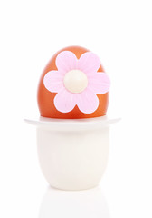 One chicken egg with pink flower in holder