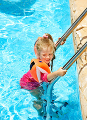 Child with armbands in swimming pool