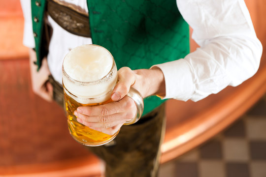 Mann in Tracht mit Bier Glas in Brauerei