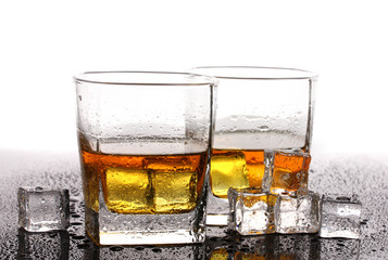 two glasses of scotch whiskey and ice on table isolated on white