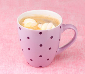 Cup of cappucino with marshmallows on pink background
